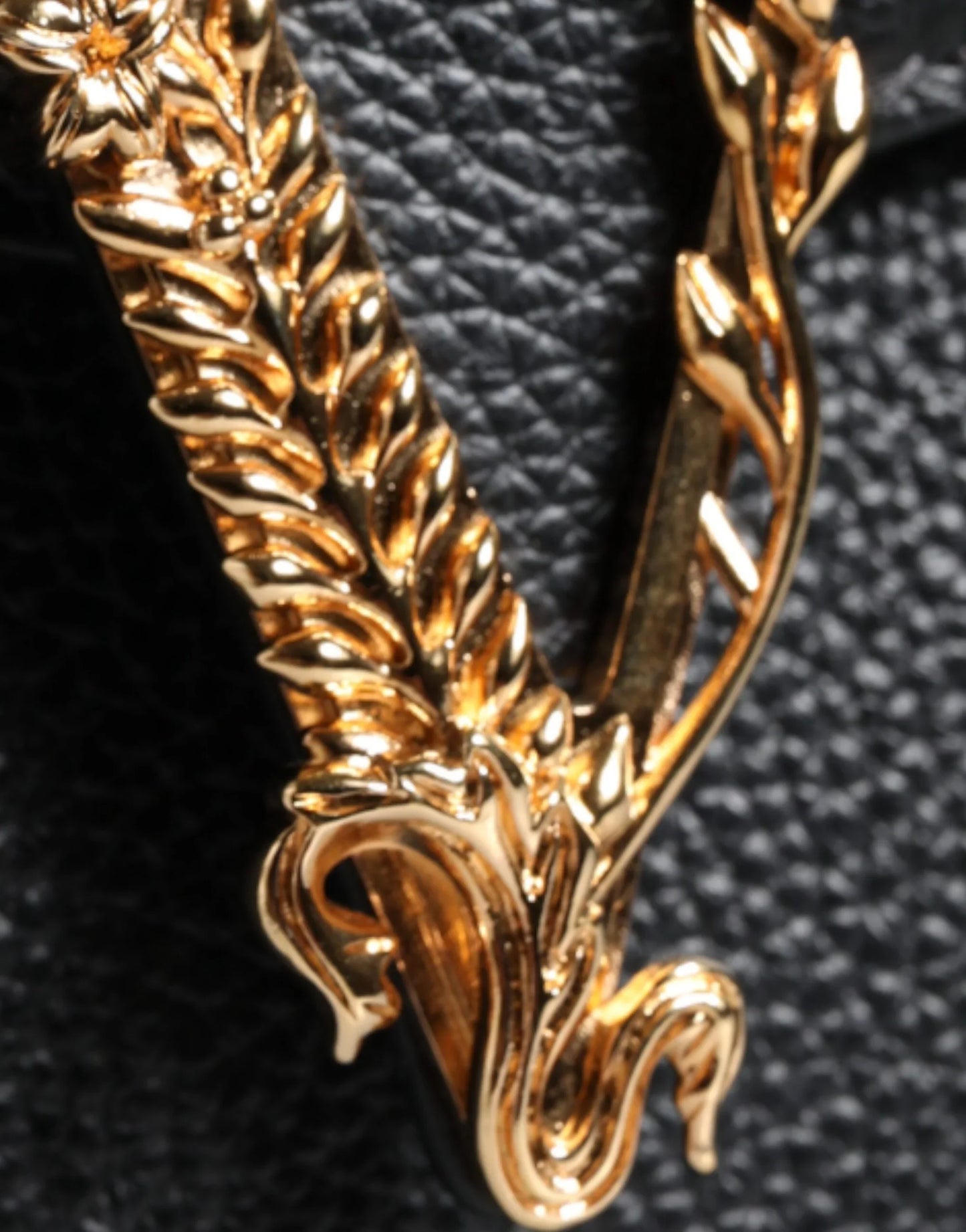 Gold ornate designer logo detail on textured black leather bag at ONJEL Fashion Boutique